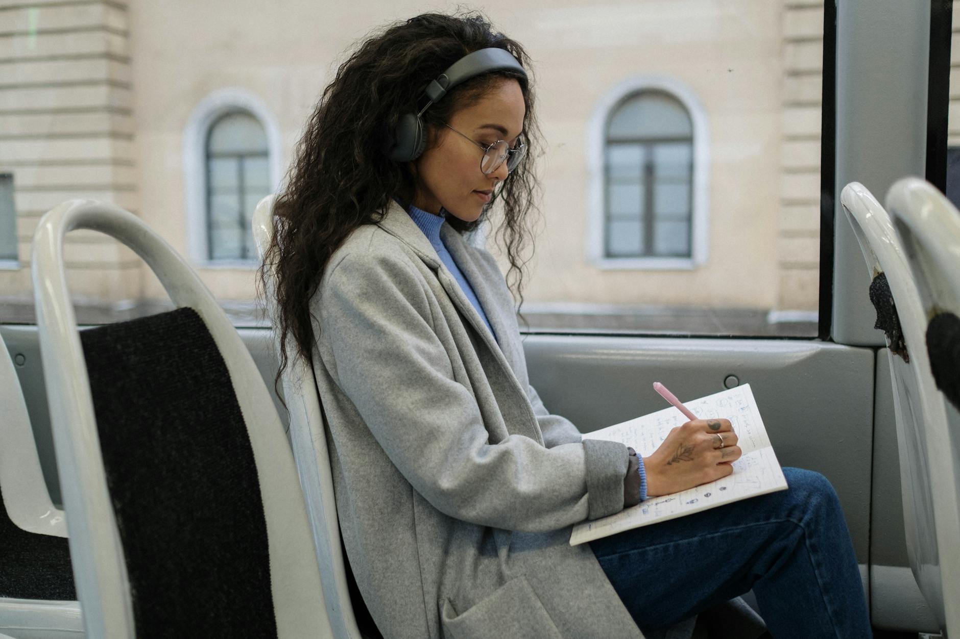 Kobieta w okularach uczy się i notuje w autobusie w trakcie podróży