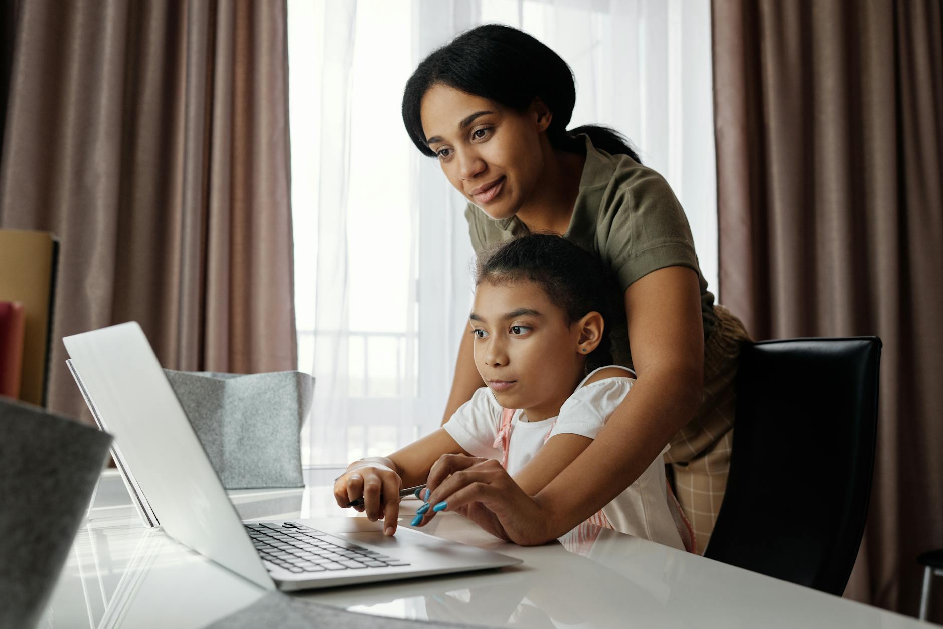 Mama pomaga córce w nauce online przy laptopie w domu