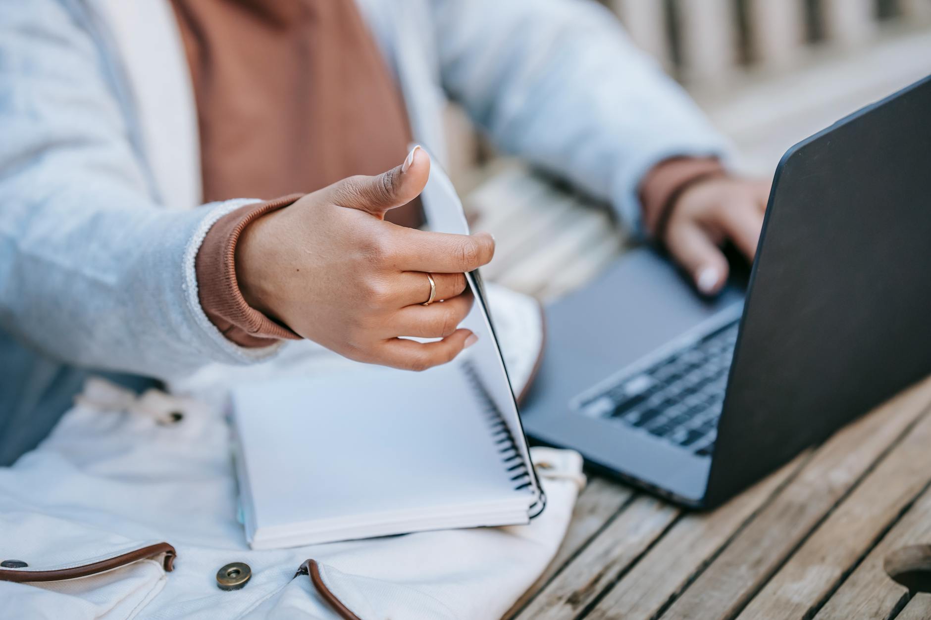 Studentka w parku łączy notatnik papierowy z nauką na laptopie