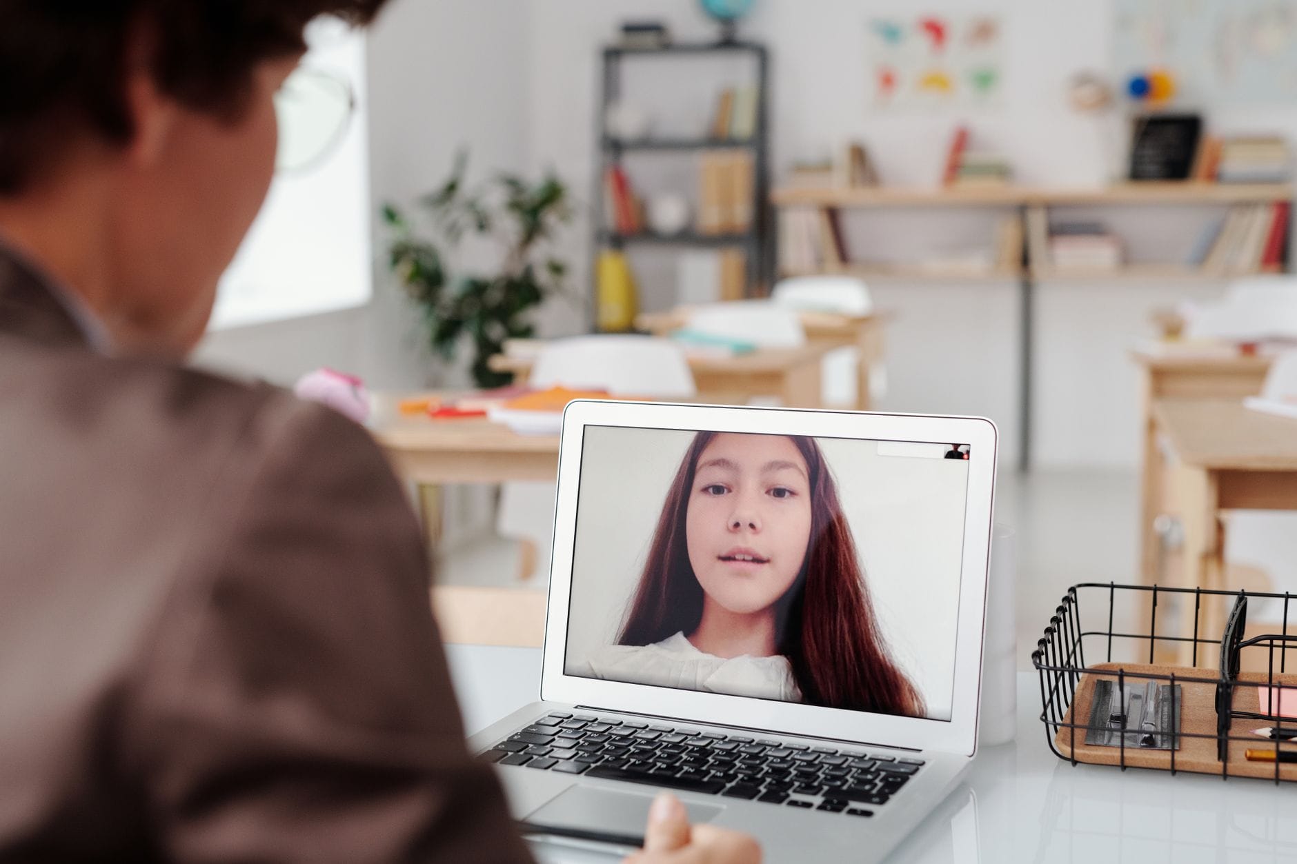Nauczyciel prowadzi lekcję online przy laptopie z uczennicą na ekranie