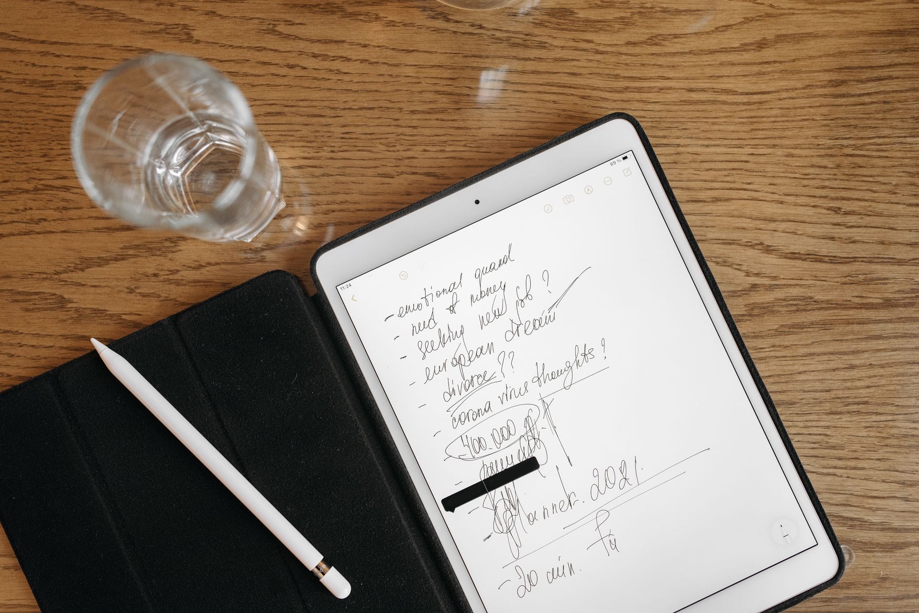 Tablet z odręcznymi notatkami, rysikiem i szklanką na drewnianym blacie