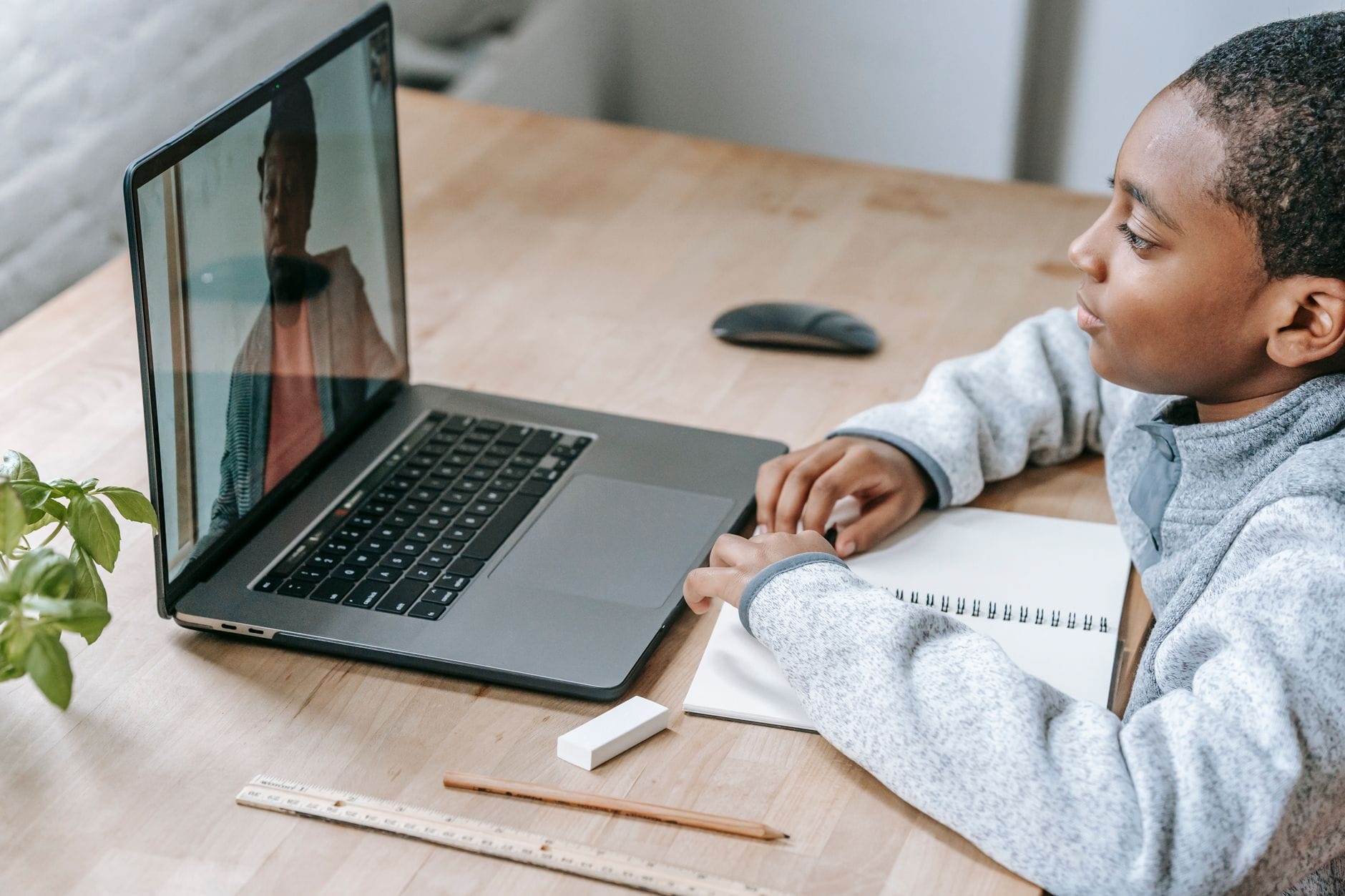 Uczeń online słuchający nauczycielki na laptopie podczas zdalnej lekcji