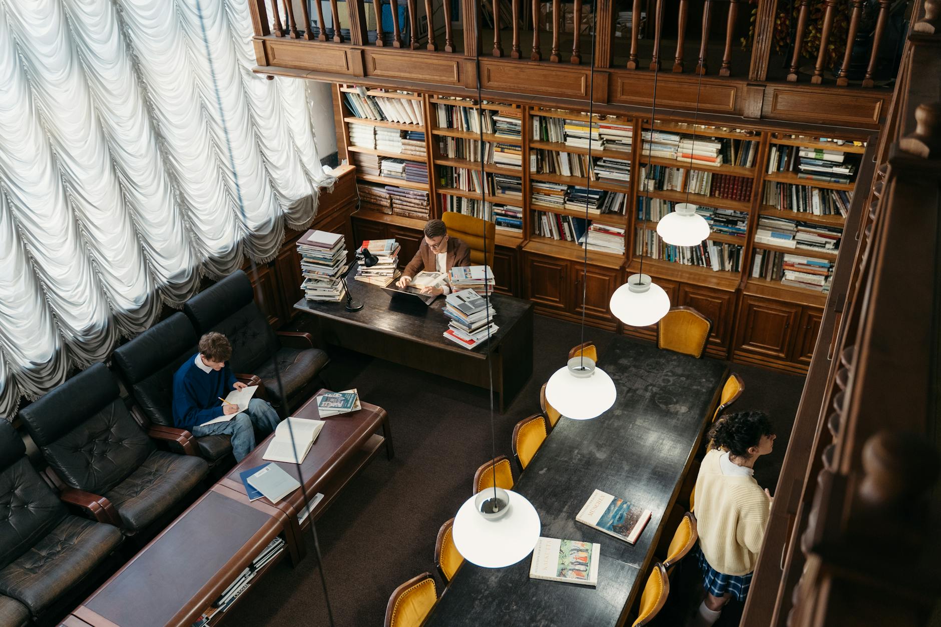 Uczniowie czytający i uczący się w przytulnej bibliotece z regałami książek