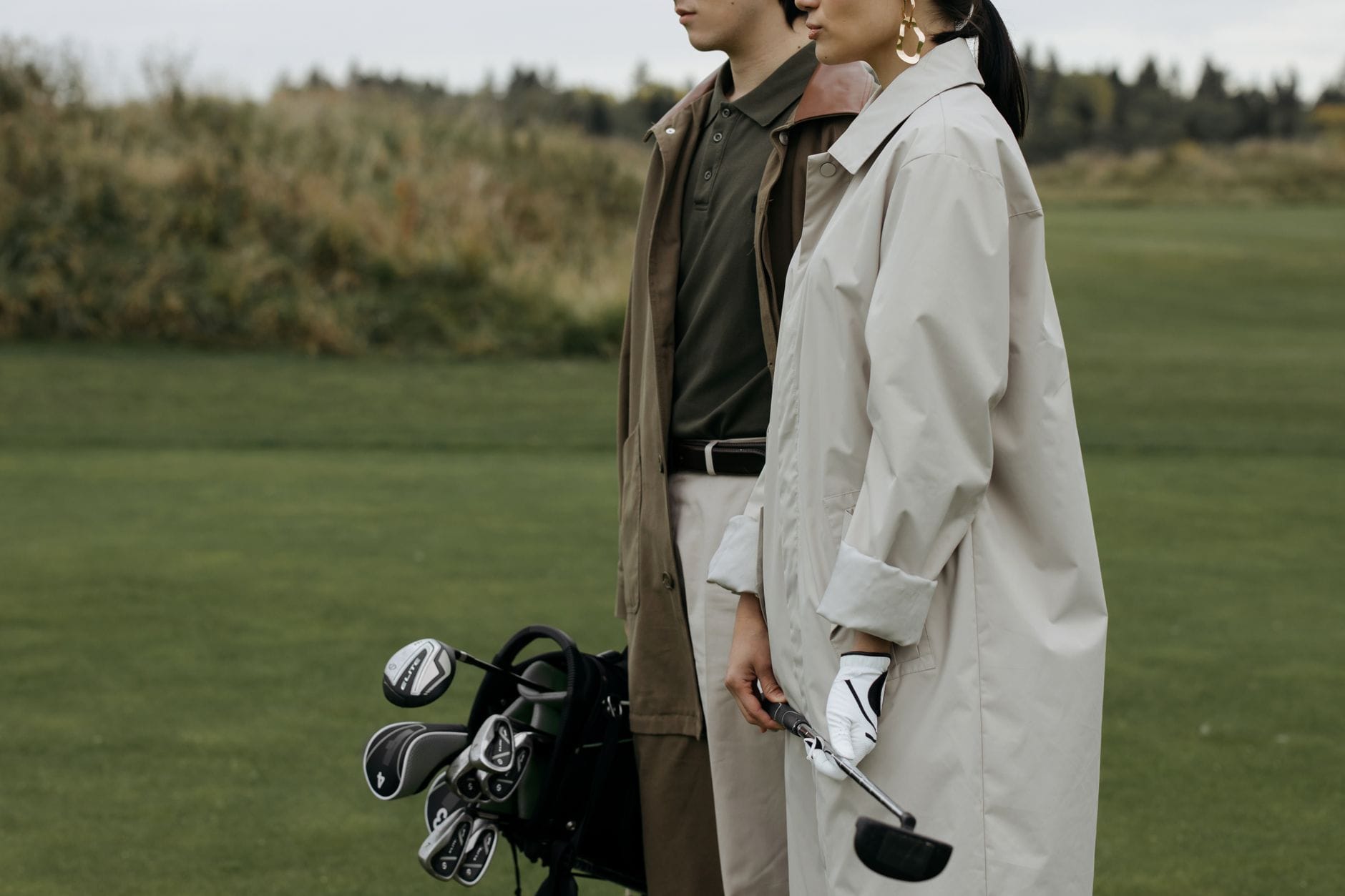 Elegancka para na polu golfowym w płaszczach przejściowych