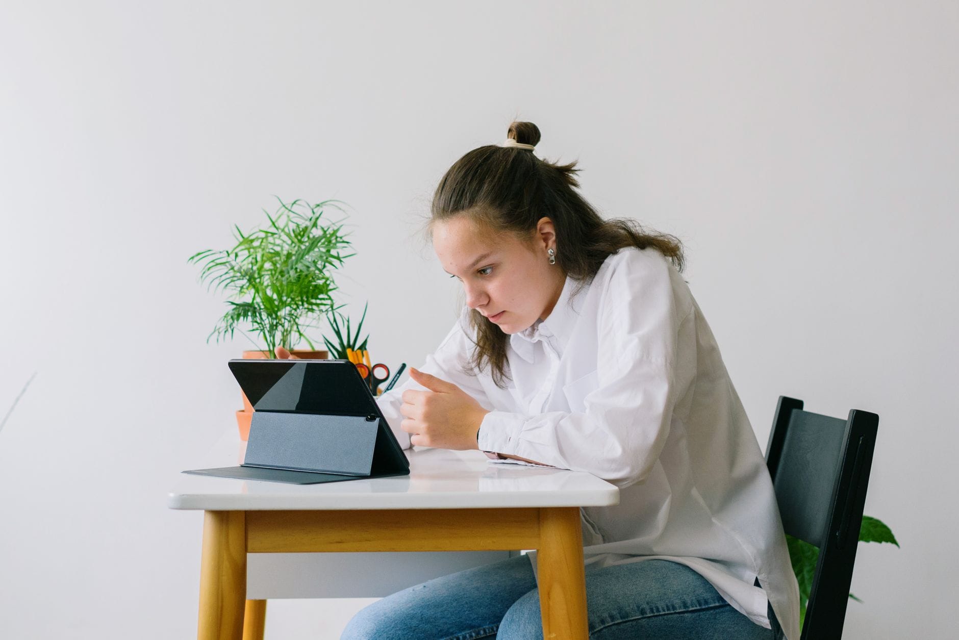 Nastolatka ucząca się w domu z tabletem w jasnym, minimalistycznym wnętrzu