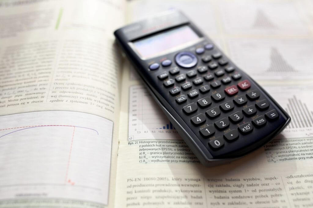 Kalkulator graficzny na otwartej książce z matematyki rozszerzonej